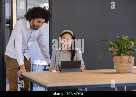 Divers collègues collaborant dans des vêtements d'affaires autour de la table de bureau tapant tablette, souris Banque D'Images
