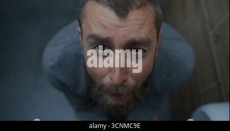 Vue de dessus sur l'homme avec l'expression faciale tendue assis sur les toilettes, souffrant de diarrhée, estomac Ache. Homme d'affaires éprouvant l'inconfort digestif et l'indigestion dans les toilettes pendant le travail au bureau. Banque D'Images