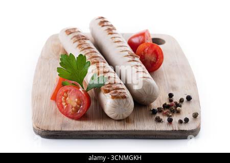 Saucisses Bratwurst grillées avec tomates cerises et persil isolées sur fond blanc Banque D'Images