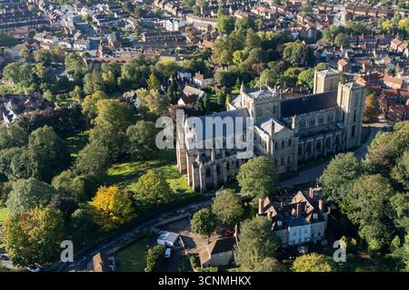 Photographie aérienne de la cathédrale de Ripon à Ripon, Yorkshire du Nord, Royaume-Uni, capturée par temps clair de fin d'été avec un ciel bleu vif et un soleil chaud mettant en valeur l'architecture gothique saisissante de la cathédrale. L'image montre l'élégant front ouest anglais ancien avec ses tours jumelles, ses pierres complexes et ses fenêtres cintrées, entouré par les rues historiques de la ville, les bâtiments voisins, les toits et les parcelles d'espaces verts, y compris les parcs et les espaces ouverts. Cette vue aérienne d'un drone capture la position centrale de la cathédrale dans la ville médiévale compacte, soulignant son rôle en tant que monument historique clé Banque D'Images