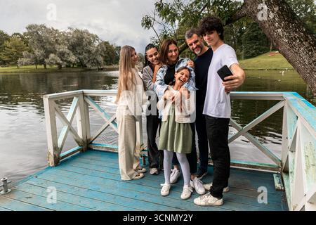 Grande famille sur le quai avec parents et enfants prenant un selfie de groupe. Banque D'Images