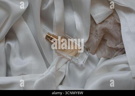 bouteille de parfum sur fond de soie blanche Banque D'Images