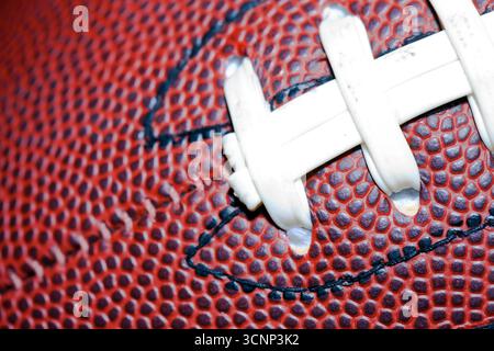 Un gros plan d'un football américain révèle une texture de cuir détaillée et des coutures précises, photographiées en studio sur fond noir, highli Banque D'Images