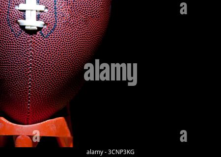 Un gros plan d'un football américain révèle une texture de cuir détaillée et des coutures précises, photographiées en studio sur fond noir, highli Banque D'Images