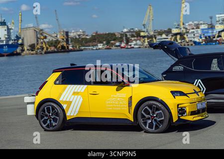 BURGAS, Bulgarie - 20 septembre 2025 : voiture électrique jaune vif design moderne et image de marque garée au bord de l'eau avec des grues industrielles et des navires Banque D'Images