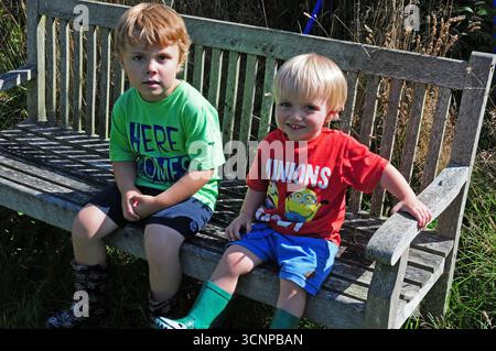 Deux petits garçons assis sur un banc de jardin. Banque D'Images