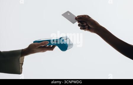 Gros plan d'une action de paiement sans contact, mettant en vedette une main tenant un lecteur de carte et une autre main présentant une carte de crédit, symbolisant le cachet moderne Banque D'Images