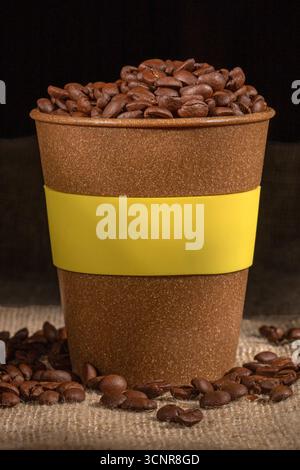 La photographie présente une tasse en plastique remplie de grains de café de haute qualité, dégageant un arôme robuste. Idéal pour les amateurs de café et un usage commercial i Banque D'Images