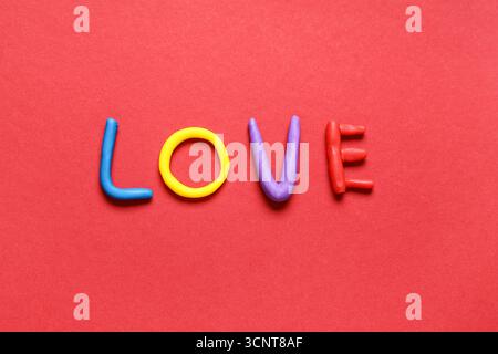 Mot AMOUR fait de pâte à jouer sur fond rouge Banque D'Images