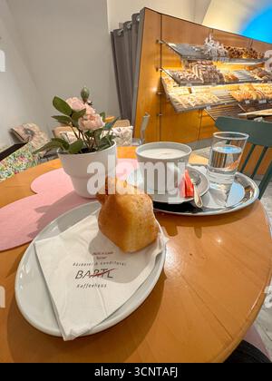 Un petit-déjeuner autrichien traditionnel dans une boulangerie locale confortable, avec pâtisserie fraîche, cappuccino et eau sur une table en bois. Banque D'Images
