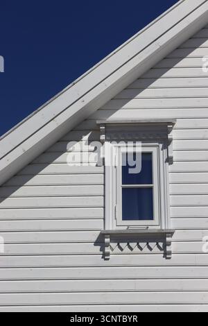 Photo recadrée mettant en évidence le détail décoratif autour d'un cadre de fenêtre d'extrémité de pignon, sur une maison blanche traditionnelle en bois dans la région de Gamle, Stavanger, Norvège. Banque D'Images