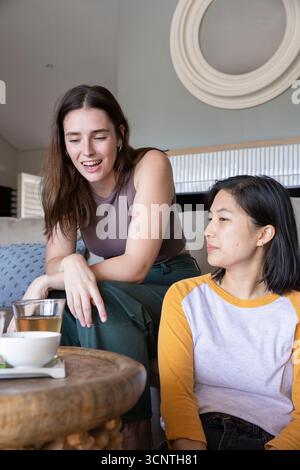 Diverses amies féminines discutant et sirotant du thé dans le salon avec table basse en bois Banque D'Images