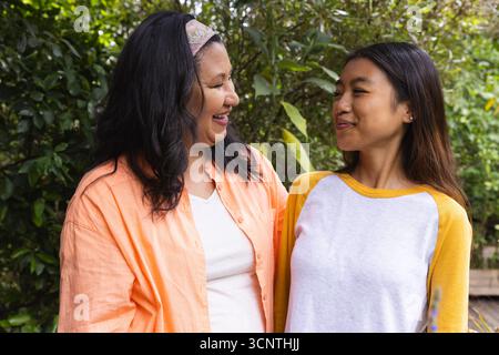 Mère et fille diverses souriant ensemble dans la cour arrière avec bandeau à motifs sur la mère Banque D'Images