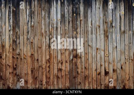 Fond vertical de planche de bois sévèrement altéré. Mur en bois noirâtre, grisâtre et brunâtre. Banque D'Images