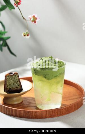 Gros plan Matcha Cloud Drink, thé vert crémeux mousse Matcha Dalgona avec eau de noix de coco glacée. Servi avec Matcha canelle coupée en deux Banque D'Images