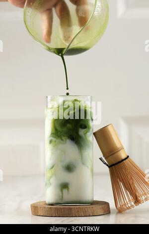Versez le thé vert Matcha sur le lait sur la table blanche, Latte Matcha Greentea glacé Banque D'Images