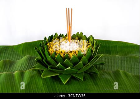 Krathong qui ont 3 bâtons d'encens et des décorations de bougie avec des fleurs blanches et jaunes met sur la feuille de banane pour Loy Krathong festival sur backgrou blanc Banque D'Images