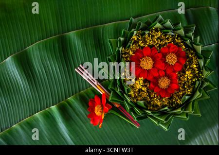 Krathong décore avec des fleurs qui ont flou l'accent de 3 bâtons d'encens et bougie mis sur la feuille de banane pour le festival Loy Krathong. Banque D'Images