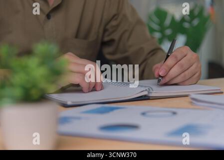 homme mains avec stylo écrire sur le bloc-notes dans le bureau.apprentissage, éducation et travail.écrit des objectifs, des plans, faire à faire et liste de souhaits sur le bureau. Banque D'Images