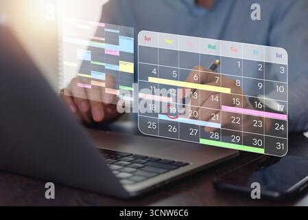 Calendrier de planification d'homme d'affaires avec calendrier numérique sur ordinateur portable. gestion du temps, planification mensuelle, suivi de la productivité. Espace de travail professionnel, Banque D'Images