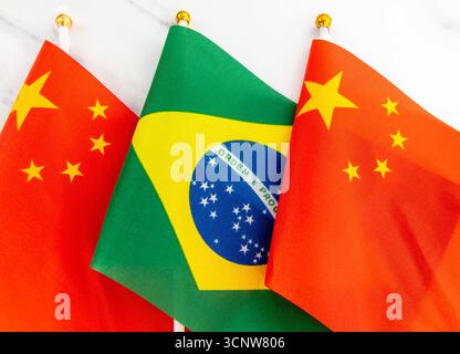 Le drapeau national du Brésil sur le mât de drapeau entre le drapeau national chinois. Un concept de relations entre la Chine et le Brésil. Banque D'Images