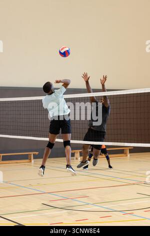 Athlètes masculins afro-américains de pointe et de blocage de volley-ball sur le filet sur le terrain de volley-ball avec kne Banque D'Images