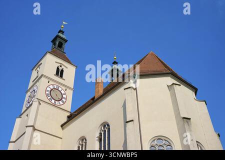 Gros plan d'une tour d'église avec horloge et toits de tuiles rouges contre un ciel bleu profond, Neupfarrkirche, Ratisbonne, Bavière, Allemagne Banque D'Images