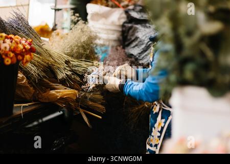 Un vendeur dans le marché animé de Seattle organise des bouquets de fleurs colorées, entourés d'une variété de fleurs et de plantes. La scène capture l'essence Banque D'Images