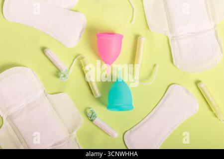 Vue aérienne des produits de santé menstruelle, y compris les coupes menstruelles colorées, les tampons et les serviettes hygiéniques. Met l'accent sur les soins périodiques écologiques et la sust Banque D'Images