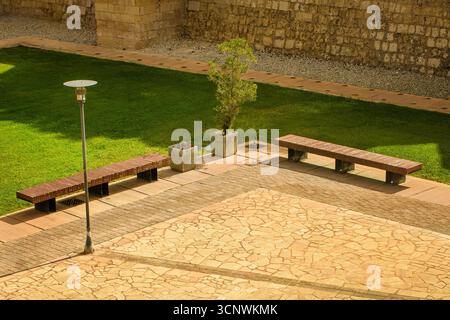 Deux bancs en bois vides, lampadaire, pelouse verte et chemins de pierre dans un parc urbain calme. Banque D'Images