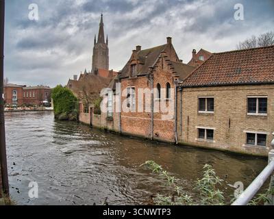 Aperçu du canal de Bruges avec la flèche de l'église - Une vue sur les célèbres canaux de Bruges avec des bâtiments historiques et la flèche de l'église notre-Dame visi Banque D'Images