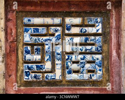 Mosaïque de carreaux abstraits dans un mur de la ville impériale - Un gros plan d'une mosaïque complexe faite de tessons de porcelaine brisée bleue et blanche, dans un re Banque D'Images
