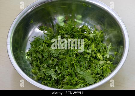 Feuilles de coriandre fraîches dans un bol en acier sur fond en bois. Coriandre est un autre nom pour les feuilles de la plante de coriandre, Coriandrum sativum. C'est le cas Banque D'Images