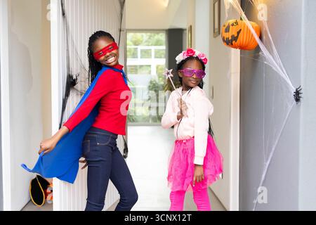 Des sœurs afro-américaines posant dans le couloir d'entrée décoré de toile avec cape bleue et baguette étoilée Banque D'Images