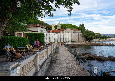 Belle promenade côtière à Opatija, Croatie, avec une passerelle en pierre le long de la mer Adriatique avec des gens se relaxant dans un café en bord de mer. La scène dans Banque D'Images