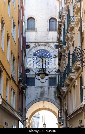 Étroite ruelle vénitienne menant à la Tour de l'horloge. Vue à travers une ruelle étroite à Venise, mettant en valeur la célèbre Tour de l'horloge St Marc avec son bleu et son or Banque D'Images