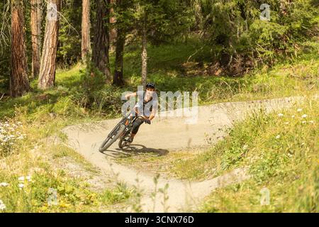 Un vététiste parcourt un sentier forestier à Zermatt, Valais, Suisse, pour montrer le frisson des sports d'aventure dans les Alpes suisses pittoresques. Banque D'Images