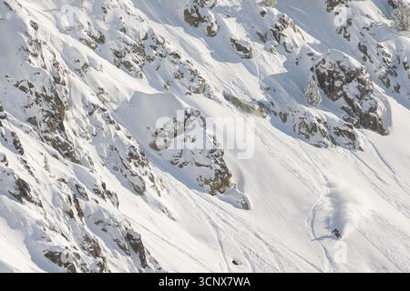 Un skieur sculpte dans la poudreuse fraîche sur une pente enneigée raide des Pyrénées. Les montagnes escarpées offrent des panoramas à couper le souffle et une spo hivernale exaltante Banque D'Images