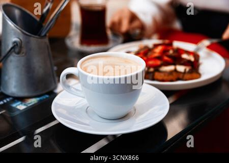 Un petit déjeuner confortable avec une tasse de café à la vapeur à côté d'une assiette de gaufres délicieuses garnies de chocolat riche et de fraises fraîches, enjo Banque D'Images
