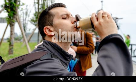 Jeune homme boit du café glacé après avoir monté le téléphérique jusqu'à la montagne Tianmen à Zhangjiajie, en Chine. L'emplacement, Tianmen Dongkai, est à 1 300 mètres Banque D'Images