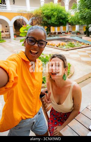 De jeunes amies multiethniques, une femme noire et une femme caucasienne, aiment prendre un selfie ensemble. Ils s'amusent et montrent des signes de paix en A. Banque D'Images