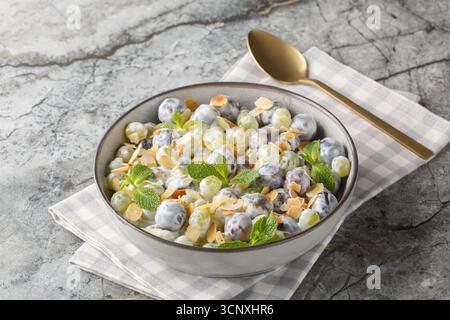 Salade de raisin Sultana douce fraîche avec flocons d'amandes, menthe, yaourt grec et vinaigrette au fromage à la crème gros plan dans une assiette sur la table. Horizontal Banque D'Images