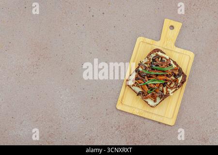 Sandwichs ouverts sains à base de plantes avec champignons Shimeji sautés. Le repas végétalien riche en protéines est servi sur une assiette blanche, fond de pierre chaud Banque D'Images