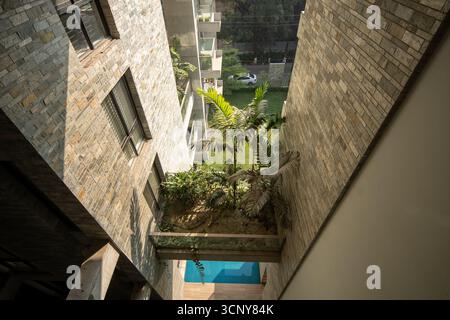 Une photo architecturale unique vue d'en haut, mettant en valeur une cour avec une petite piscine et des plantes luxuriantes nichées entre deux bâtiments modernes Banque D'Images