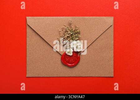Enveloppe avec sceau de cire isolé sur fond rouge Banque D'Images