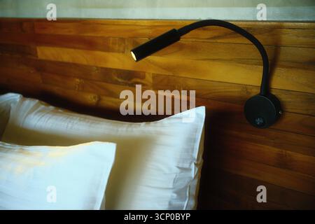 Lampe de chevet noire réglable montée sur une tête de lit en bois Banque D'Images