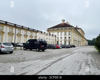 Oberschleissheim, Allemagne - 25 septembre 2022 : extérieur du palais allemand Schleissheim avec fenêtres cintrées, façade jaune et voitures garées le long d'un gravier Banque D'Images