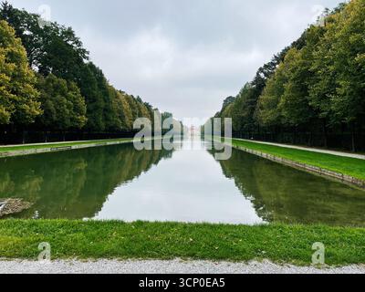 Oberschleissheim, Allemagne - 25 septembre 2022 : canal calme bordé d'arbres et de verdure dans le parc allemand du palais de Schleissheim. Banque D'Images