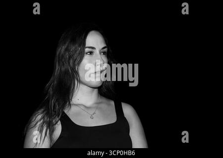 Femme contemplant avec une expression sérieuse, regardant loin dans un portrait dramatique en noir et blanc Banque D'Images