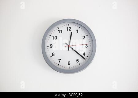 Moderne, analogique, grande horloge à visage blanc accrochée sur un mur blanc. Gros plan intérieur, personne Banque D'Images